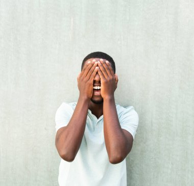 Portrait laughing young African American man with hands covering face