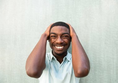 Close up portrait laughing young African American man with hands behind head