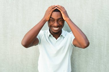 Close up front portrait laughing young African American man with hands on head