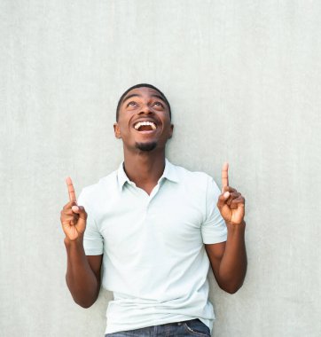 Portrait happy young African American man looking up and pointing fingers