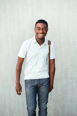 Portrait smiling young African American man walking with shoulder bag