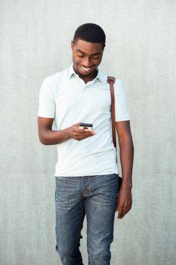 Portrait cool young black man walking with cellphone and bag