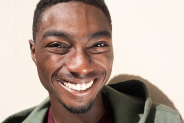 Close up portrait handsome young African American man smiling by white background 