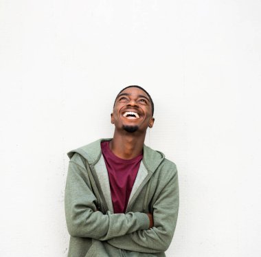 Portrait young african American man laughing and looking up with arms crossed against white background 