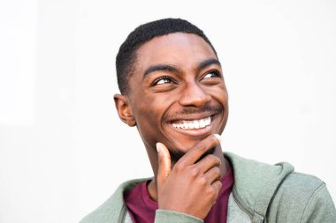 Close up portrait handsome young African American man laughing and looking away by white background 