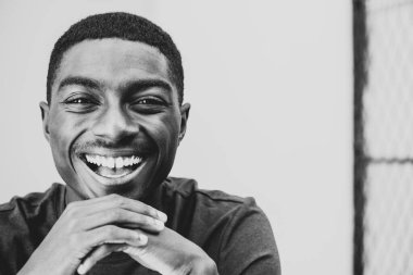 Close up black and white portrait smiling young black man with hands to chin