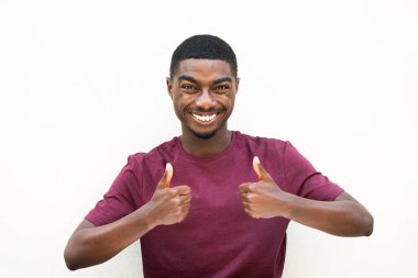 Portrait smiling black man with thumbs up hand sign by isolated white backgorund 