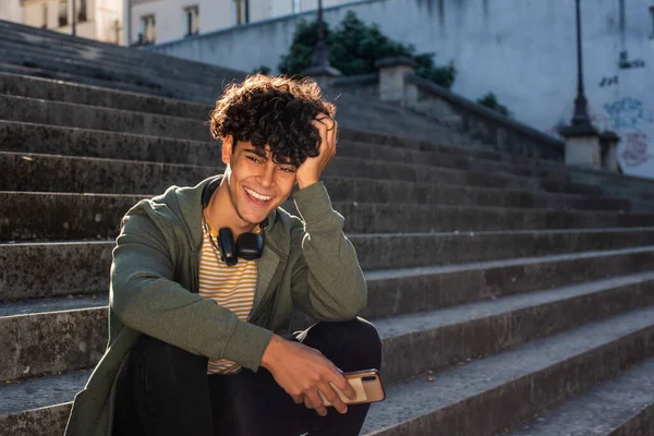 Portrait happy young guy sitting on steps outside