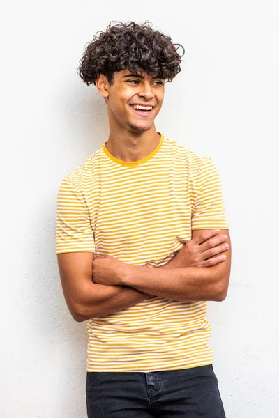 Portrait smiling young North African man with arms crossed by white background 