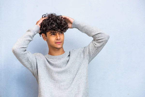 Portrait handsome young North African man posing with hands in hair