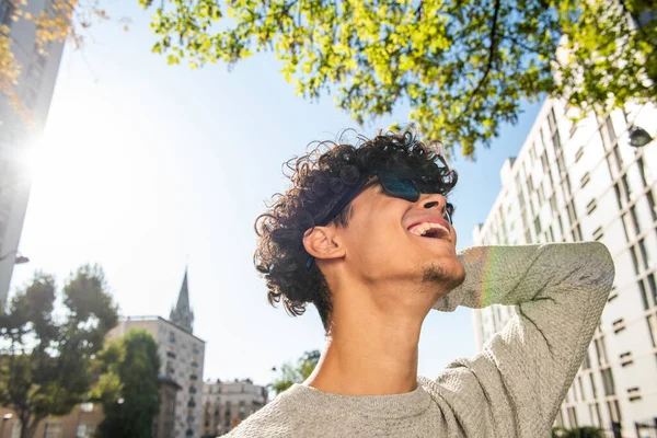 Close up portrait young man laughing with sunglasses and hand behind head