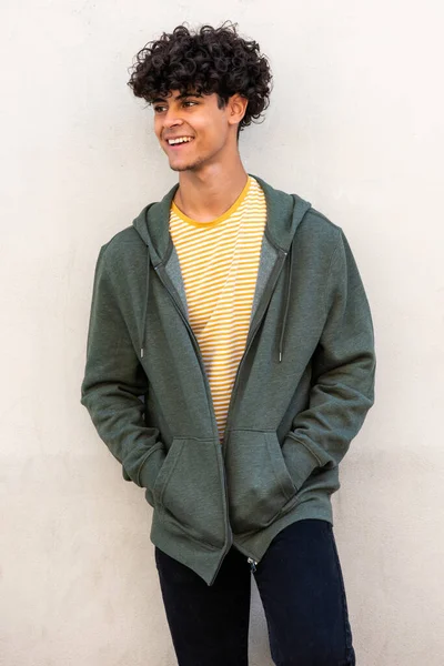 Portrait cool young male model smiling and posing by white wall