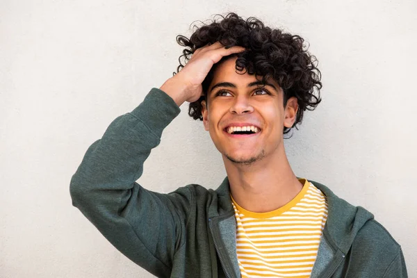 Close up portrait young man laughing with hand in hair and looking up