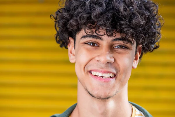 Close up portrait young North African man smiling against yellow background 