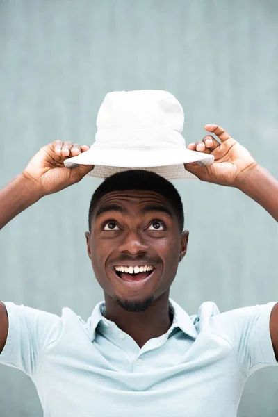 閉じる上のポートレート陽気な若いですアフリカ系アメリカ人男性保持帽子上 — ストック写真