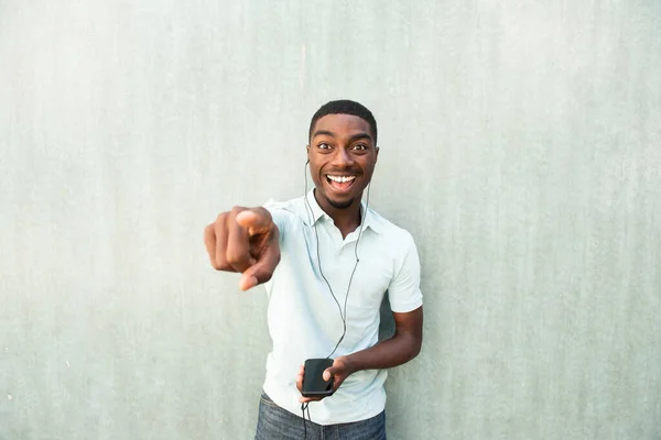 Portrait Laughing Young Black Man Mobile Phone Earbuds Pointing Finger — Stok fotoğraf