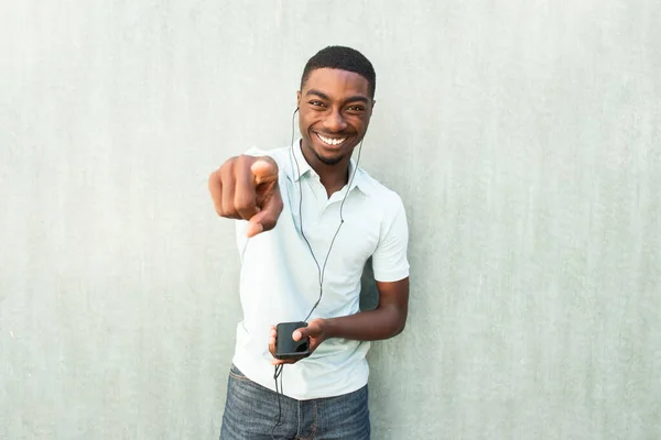 Retrato Riendo Joven Hombre Negro Con Teléfono Celular Auriculares Señalando —  Fotos de Stock