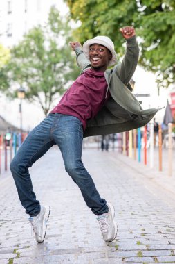 Full body portrait happy young man standing on toes on street
