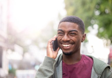 Close up portrait smiling young african American man using cellphone outdoors