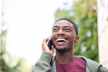Close up portrait happy young black man talking with cellphone 