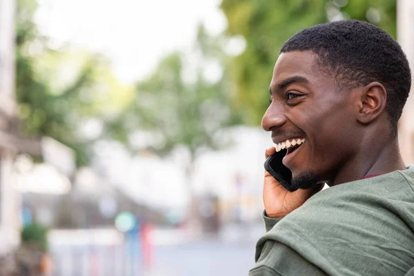 閉じるサイドポートレート幸せな若いですアフリカ系アメリカ人男性と話して携帯電話外 — ストック写真