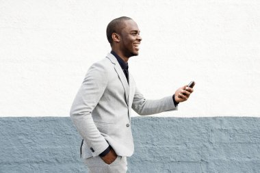 Duvarda cep telefonuyla yürüyen Afrikalı Amerikalı iş adamının profil portresi