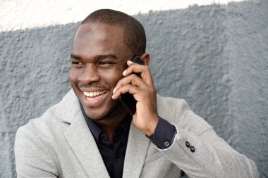 Yakışıklı Afro-Amerikan bir adamın yakın portresi. Gülümsüyor ve telefonla konuşuyor.