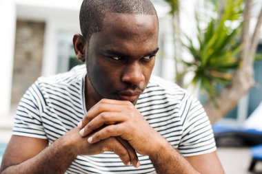 Afrikalı bir adamın portresini yakın çekimde otururken düşüncelere dalmış.