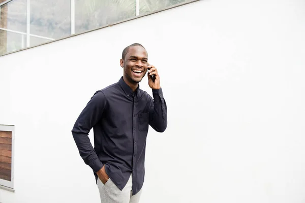 Retrato Hombre Afroamericano Sonriente Caminando Con Teléfono Móvil Por Pared —  Fotos de Stock