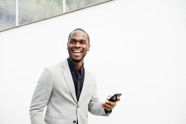 Porträtt Stilig Afroamerikansk Affärsman Ler Med Telefon Vid Vit Vägg — Stockfoto