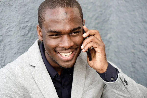 ハンサムなアフリカ系アメリカ人男性の笑顔と携帯電話との話の肖像画を閉じます — ストック写真
