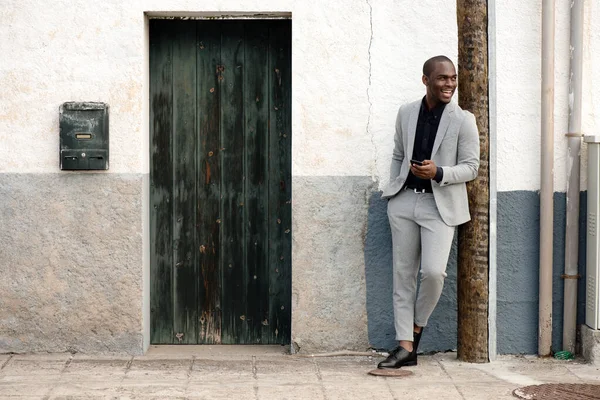 Полный Портрет Улыбающегося Африканского Бизнесмена Стоящего Стены Мобильным Телефоном — стоковое фото
