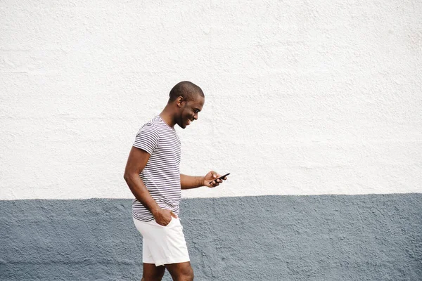 プロフィール肖像画アフリカ系アメリカ人のマニアTシャツとショートパンツ携帯電話で歩く — ストック写真