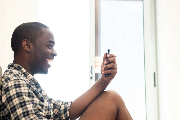Portret Lachende Afro Amerikaanse Man Zit Met Mobiele Telefoon Thuis — Stockfoto