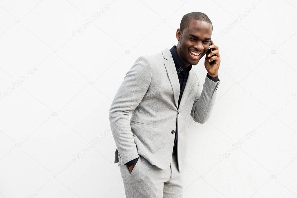 Portrait of African American businessman laughing while talking with cellphone against isolated white background 