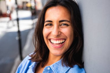 Güzel genç bir kadının portresini yakından çek. Duvara yaslan ve gül.