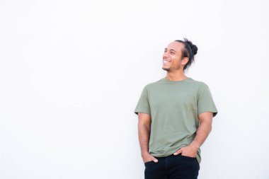 Saçını toplamış, elleri ceplerinde mutlu bir adam beyaz arka plana bakıyor.