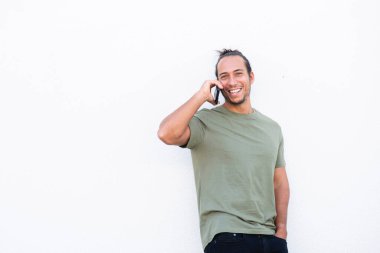 Saçını toplayan mutlu adam beyaz arka planda cep telefonuyla konuşuyor.