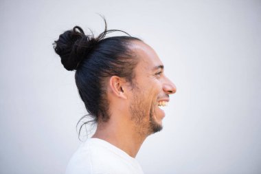 Beyaz arka planda saç topuzu çeken neşeli bir adamın profili.