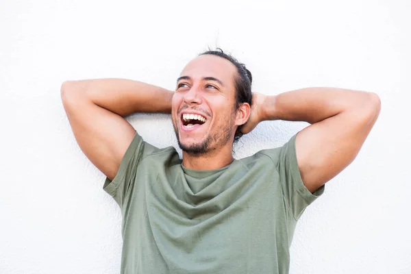 Man with hands behind head laughing over white background