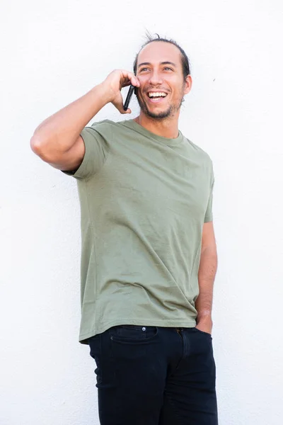 Happy man with pulled up hair bun talking on mobile phone over white background