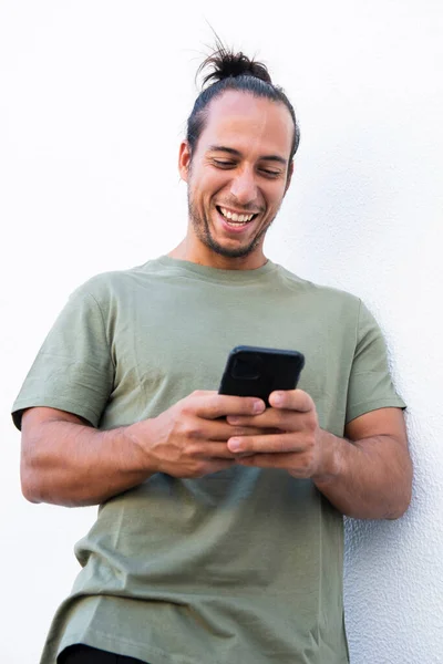 Happy man with hair bun text messaging using mobile phone over white background