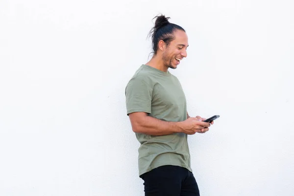 Cheerful man with pulled up hair bun using mobile phone over white background