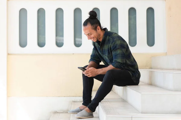 階段の屋外で携帯電話を使用して笑顔の男のテキストメッセージ — ストック写真