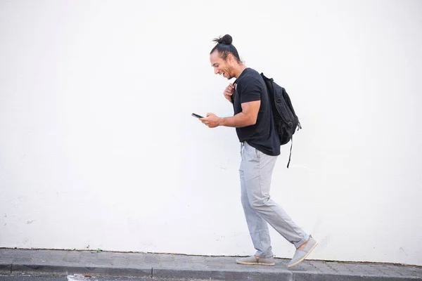 Happy Man Carrying Backpack While Walking Text Messaging Using Mobile — ストック写真