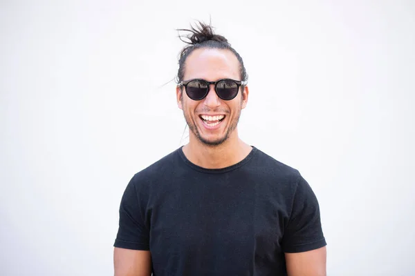 Cheerful handsome man with hair bun and sunglasses against white wall