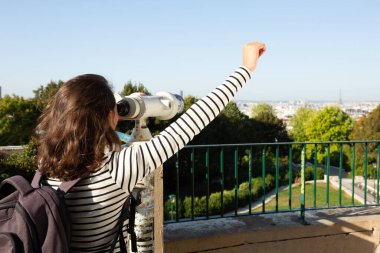 Teleskopla kollarını kaldırmış genç bir kadının portresi.