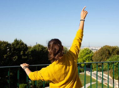 Parkta el kaldırılmış genç bir kadının portresi.