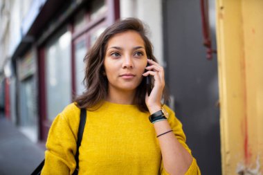 Şehirde cep telefonuyla konuşan genç bir kadın portresi