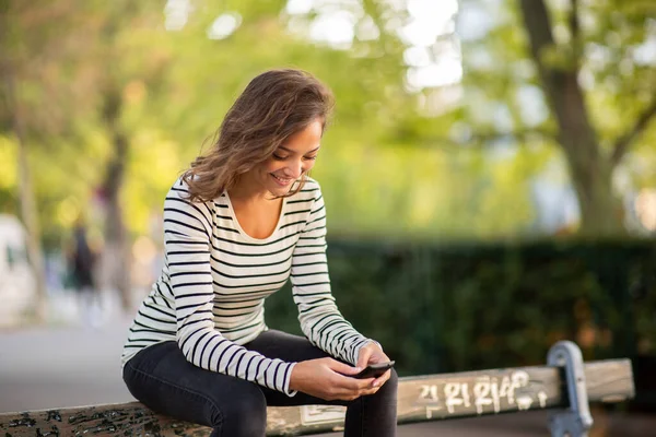 Portrait Happy Young Woman Sit Bench Looking Cellphone — Stok Foto